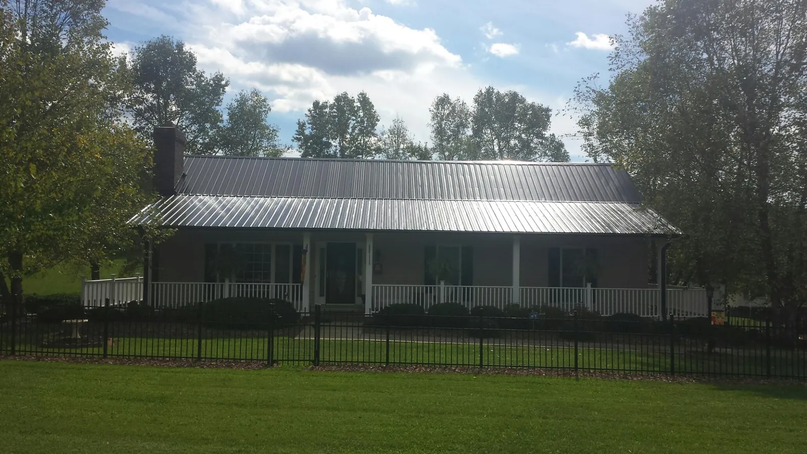 Gray metal roof on a brick ranch with a full width front porch — Gutter Guard Installation work by our crew in Walkersville