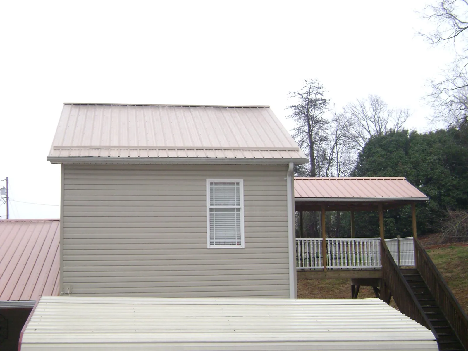 Tan metal roofs on a two story addition and attached porch, from a Roof Replacement job in Walkersville